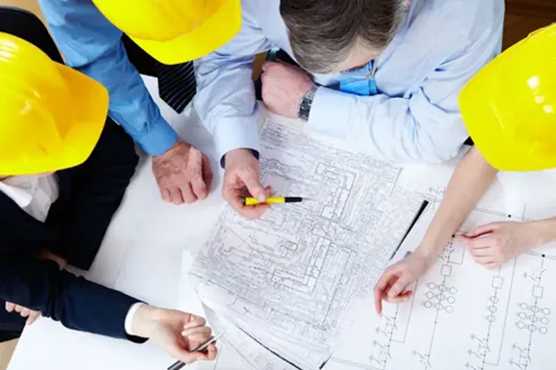 HVAC and engineers looking at blueprints around a table.